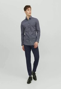 Mörkblå rutmönstrad skjorta med knapp-up, åtsittande design, långa ärmar och spridd krage, tillsammans med slim-fit marinblå byxor och svarta skor.