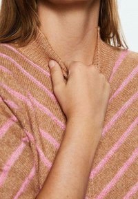 Suéter marrón a rayas con líneas rosas, con un cuello acanalado. Textura suave con un ajuste relajado, mano reposando en el escote.