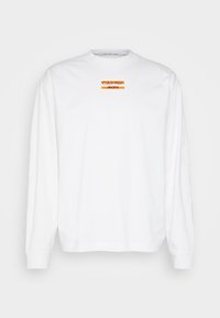 Fehér, hosszú ujjú, pamut póló, kerek nyakkivágással, középen narancssárga és fekete "Calvin Klein Jeans" logóval.