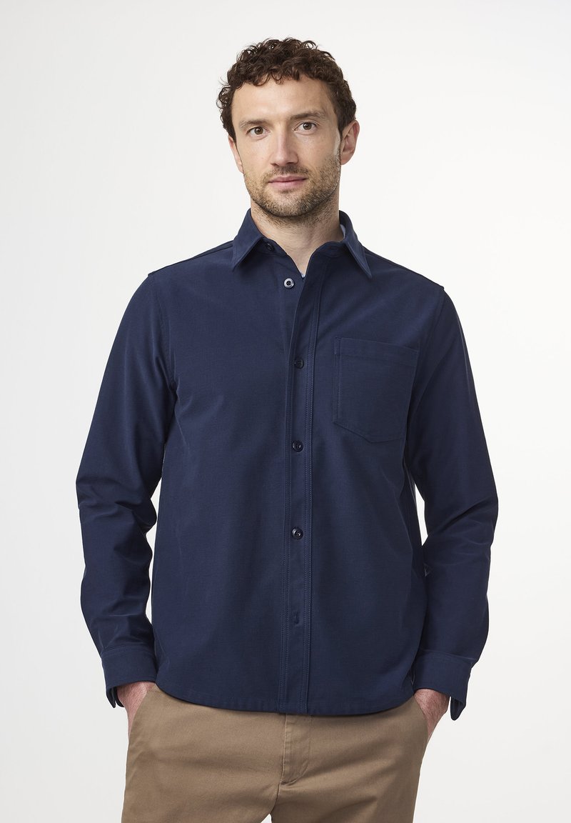 Navy blue button-up shirt in a soft fabric with a chest pocket, long sleeves, and a classic collar, paired with khaki pants.