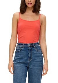 Koralkowy top na ramiączkach z cienkimi paskami zestawiony z wysokimi granatowymi dżinsami. Gładki materiał o dopasowanym kroju i klasyczny pięciopocketowy styl.
