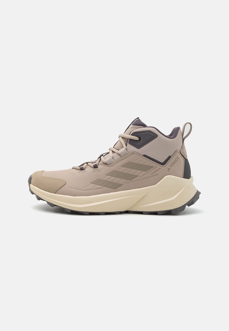 Beżowe buty turystyczne o solidnej konstrukcji, z teksturowaną cholewką, sznurowaniem i elastyczną podeszwą. Wyposażone w szare akcenty i wzmocniony zapiętek dla lepszego wsparcia.