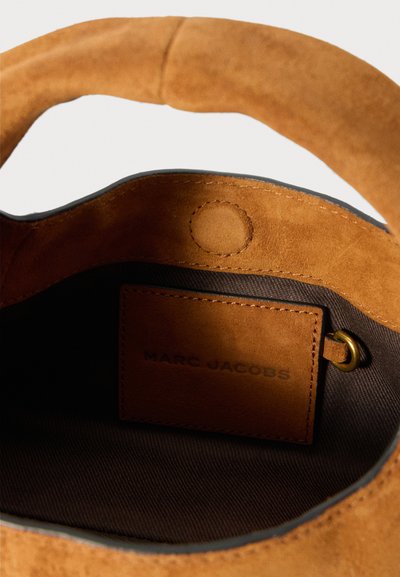 Brown suede bucket bag with dark fabric interior and stitched leather label inside reading "Marc Jacobs."