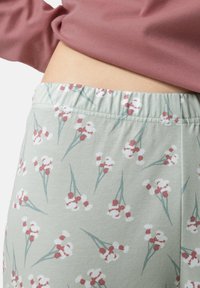 Lichtgroene pyjamabroek met een bloemenpatroon, gekenmerkt door rode en witte bloemen, elastische tailleband en zachte katoen materiaal.