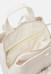 Mochila de cuero blanco con un diseño estructurado, compartimento principal con cremallera, bolsillo interior con un acento amarillo brillante y herrajes plateados.