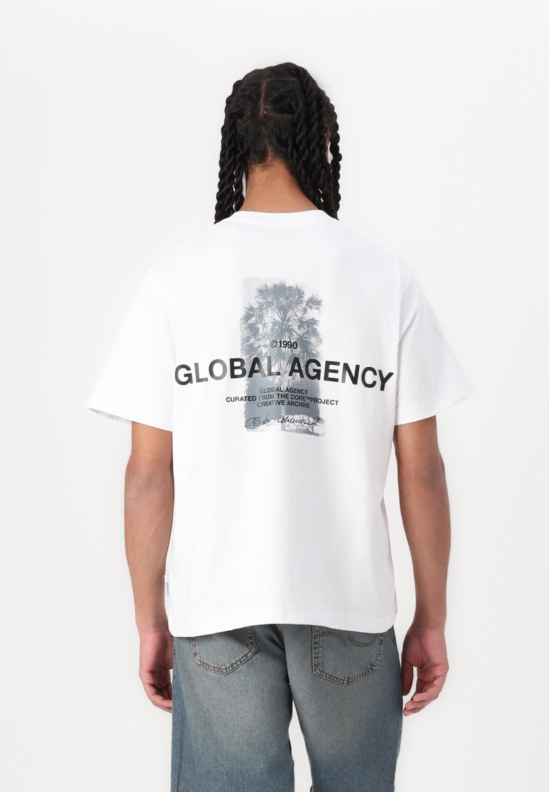 Bílý bavlněný tričko s grafickým potiskem palem a textem "GLOBAL AGENCY" na zadní straně, v uvolněném střihu a s krátkými rukávy.