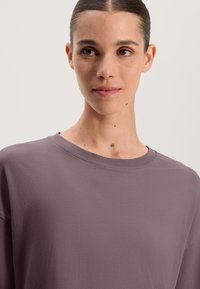 Volný tričko s kulatým výstřihem v tlumené mauve barvě. Vyrobeno z měkké látky s hladkým povrchem, s minimem švů a uvolněným designem.