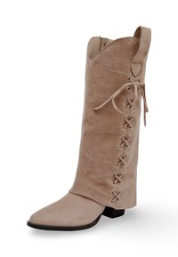 Botte hautes en suede beige, avec un bout pointu, un talon plat et un design à lacets avec des œillets métalliques le long du côté.