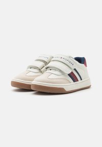 White leather sneakers with suede accents, two Velcro straps, navy and red stripes, and a rubber sole featuring a textured pattern.