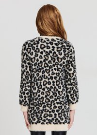 Pull oversized imprimé léopard en tissu doux et moelleux. Base crème avec des taches noires et brunes. Manches longues et finition côtelée.