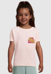 Lichtroze katoenen T-shirt met de tekst "GIRL POWER SQUAD" in vetgedrukte, multiculturele letters aan de linkerkant van de borst. Korte mouwen, ronde hals.