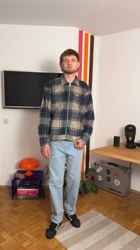 Casaco de flanela xadrez em azul e bege com fecho à frente, combinado com jeans azul claro. Ténis pretos de desporto completam o visual.