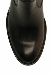 Scarpa in pelle nera lucida vista dall'alto, che mostra la punta arrotondata e i dettagli della cucitura lungo il bordo della suola.