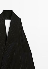 Zwarte kimono met een diepe V-hals, voorzien van diagonale witte streepjes. Het materiaal lijkt glad met een lichte glans. De randen zijn op maat gemaakt.