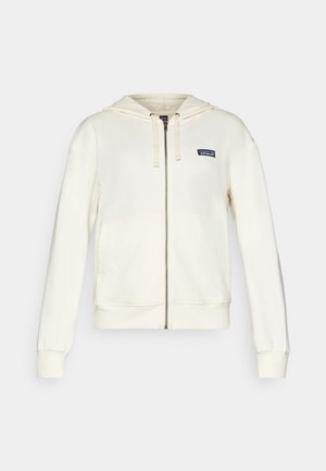 Cream hooded zip-up sweatshirt made of soft fabric. Features front pockets and a small logo patch on the left chest. Ribbed cuffs and hem.