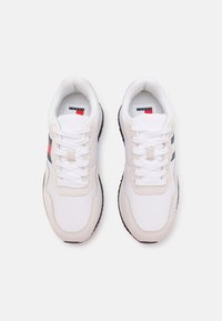 Vita sneakers med en överdel i mocka och mesh, med grå och röda detaljer, rund tå, gummisula och platta snören. Perspektiv från ovan.