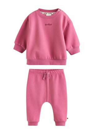 Pink toddler-sized sweatshirt and matching pants, elastic waistband with drawstring, ribbed cuffs, and "smiles" embroidered on the top center.
