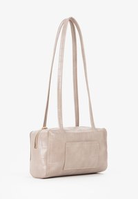 Borsa in pelle con stampa a coccodrillo di colore beige chiaro, con chiusura a zip, due manici lunghi e una tasca piatta sul davanti.