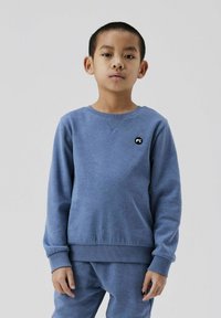 Sudadera de algodón azul con mangas largas, puños acanalados, cuello redondo, que presenta un pequeño logo negro en la parte superior izquierda. Textura suave.
