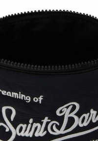 Borsa in tessuto nero con testo bianco ricamato "sognando Saint Barth." Presenta una chiusura con zip e un interno liscio e strutturato.