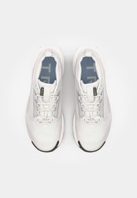 Chaussures de sport blanches avec une tige en maille texturée, des accents tonal, une semelle rembourrée et une semelle extérieure en caoutchouc noir contrastant. Comprend des lacets plats.