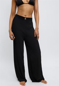 Melni plaša piegriezuma bikses no viegla auduma ar gludu tekstūru un redzamu metāla sprādzi jostasvietā.