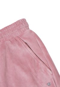 Zachte roze velours broek met elastische tailleband, zijzak en klein rond metalen logo vlakbij de zoom.