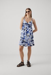 Rochie cu un model floral în alb și albastru, cu accente negre, având bretele subțiri ajustabile și o fustă cu volane în straturi.
