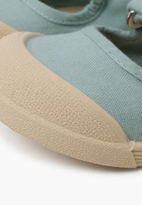 Scarpa in tela blu con una punta in gomma beige chiaro e testurizzata e cuciture bianche. Presenta fori per i lacci e una forma liscia e arrotondata.
