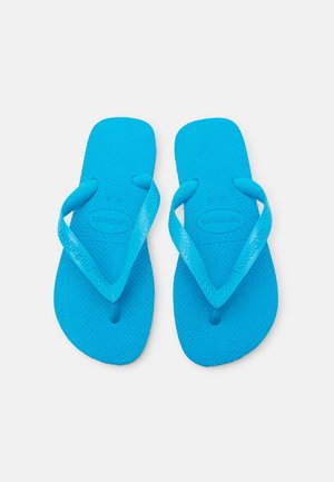 Chanclas de goma azules con suelas texturizadas y tiras anchas, que cuentan con un logotipo de la marca en la tira y un diseño plano para un calce fácil.