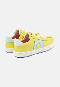 Žluté kožené sneakersy s světle modrými akcenty a bílým podpatkem, které mají bílé tkaničky a texturovanou podrážku. Ležérní design s prošívanými detaily.