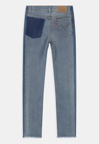 Jasnoniebieskie dżinsy z ciemniejszym niebieskim naszywką na tylnej kieszeni, postrzępione końcówki i metka na pasku.