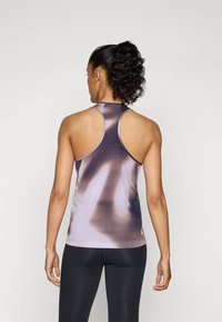 Ärmelloses Sporttanktop in schattierten Lila- und Brauntönen, mit einer glatten Textur und Racerback-Design. Mit minimaler Markenkennzeichnung am Saum.