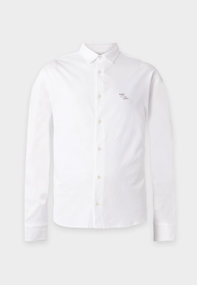 Chemise blanche à manches longues avec boutons, col pointu et petit logo brodé sur la poitrine gauche.