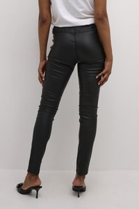 Schwarze Leggings aus Kunstleder mit glatter Textur, slim fit und elastischem Bund. Tragen mit schwarzen High-Heel-Mules.