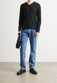 Musta v-kaula-aukollinen neulepaita, siniset farkut ja mustat nilkkurit. Asusteina musta olkalaukku. Yksinkertainen, rento asu.