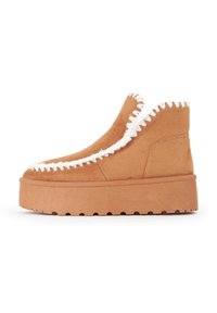 Stivaletti alla caviglia in suede beige con orlo cucito bianco. Presentano una suola piatta spessa con una finitura testurizzata. Design slip-on, senza lacci.