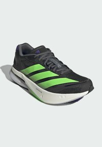 Baskets de course noires avec un design à rayures vertes et noires, tige en mesh gris, accents violets, et une semelle extérieure blanche portant l'inscription "LIGHTSTRIKE PRO".