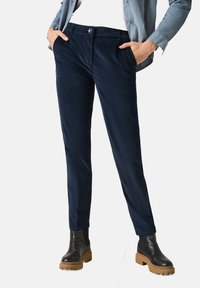 Marineblauwe corduroy broek met een slim fit, voorzakken en een enkele knoopsluiting. Gepaarde met zwarte enkellaarzen met een stevige zool.