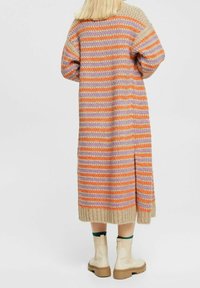 Lång stickad cardigan med flerfärgade ränder i orange, lavendel och beige. Tillverkad av strukturig garn, med räfflad nederkant och sidoklaff.