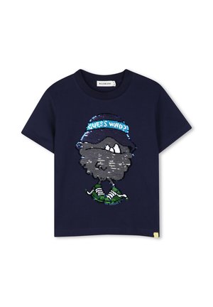 Donkerblauw T-shirt met korte mouwen met een pailletten cartoon gezicht dat een hoed draagt met de tekst "GUESS WHO?" en groene sneakers.