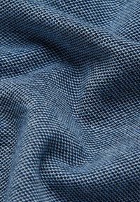 Teksturowana niebieska tkanina o drobnym splocie, z delikatnym połyskiem i miękkimi fałdami. Ogólny wygląd jest głęboki i bogaty w kolorze.