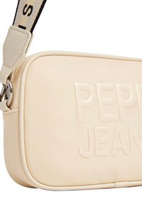 Crème-kleurige synthetische handtas met reliëf "PEPE JEANS" logo, rechthoekige vorm en verstelbare schouderband met contrasterende zwarte tekst.