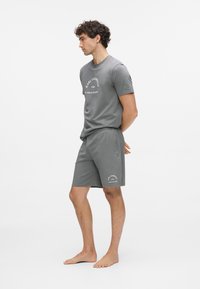 Hall halli puuvillasegusega lühikeste varrukatega t-särk, millel on logotrükk. Sobitatud hallide lühikeste pükstega, mõlemad valmistatud siledast, kergest kangast.