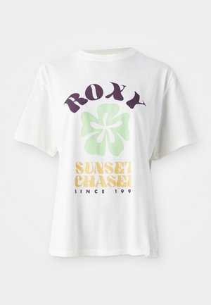 T-shirt en coton blanc avec un grand logo "ROXY" violet, un design de fleur verte, et "SUNSET CHASE" en jaune, avec des manches courtes décontractées.
