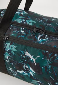 Sportduffelbag met een groen en zwart abstract patroon, met ritszakken en een opvallend zilveren logo op gestructureerde stof.
