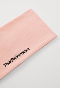 Roze katoenen haarband met een gladde textuur, voorzien van een zwart geborduurd 'Peak Performance' logo langs de onderrand.