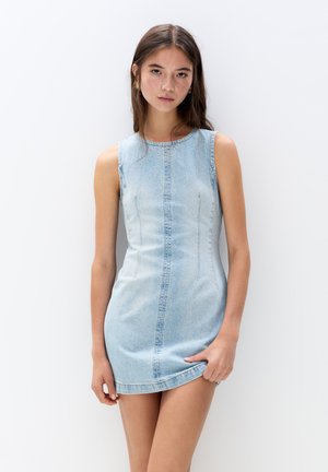 Denim mini dress in light blue, sleeveless, featuring a fitted silhouette, curved neckline, and subtle vertical stitching details.