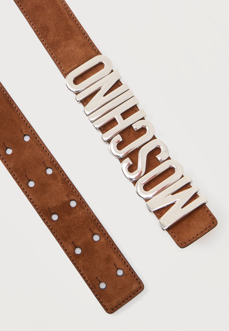 Brown suede belt with multiple adjustment holes and large silver metallic letters spelling "MOSCHINO" as the buckle.