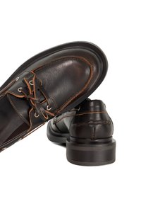 Brown leather boat shoes with contrasting stitching, rounded toe, lace-up design, and a low stacked heel. Smooth texture and classic shape.